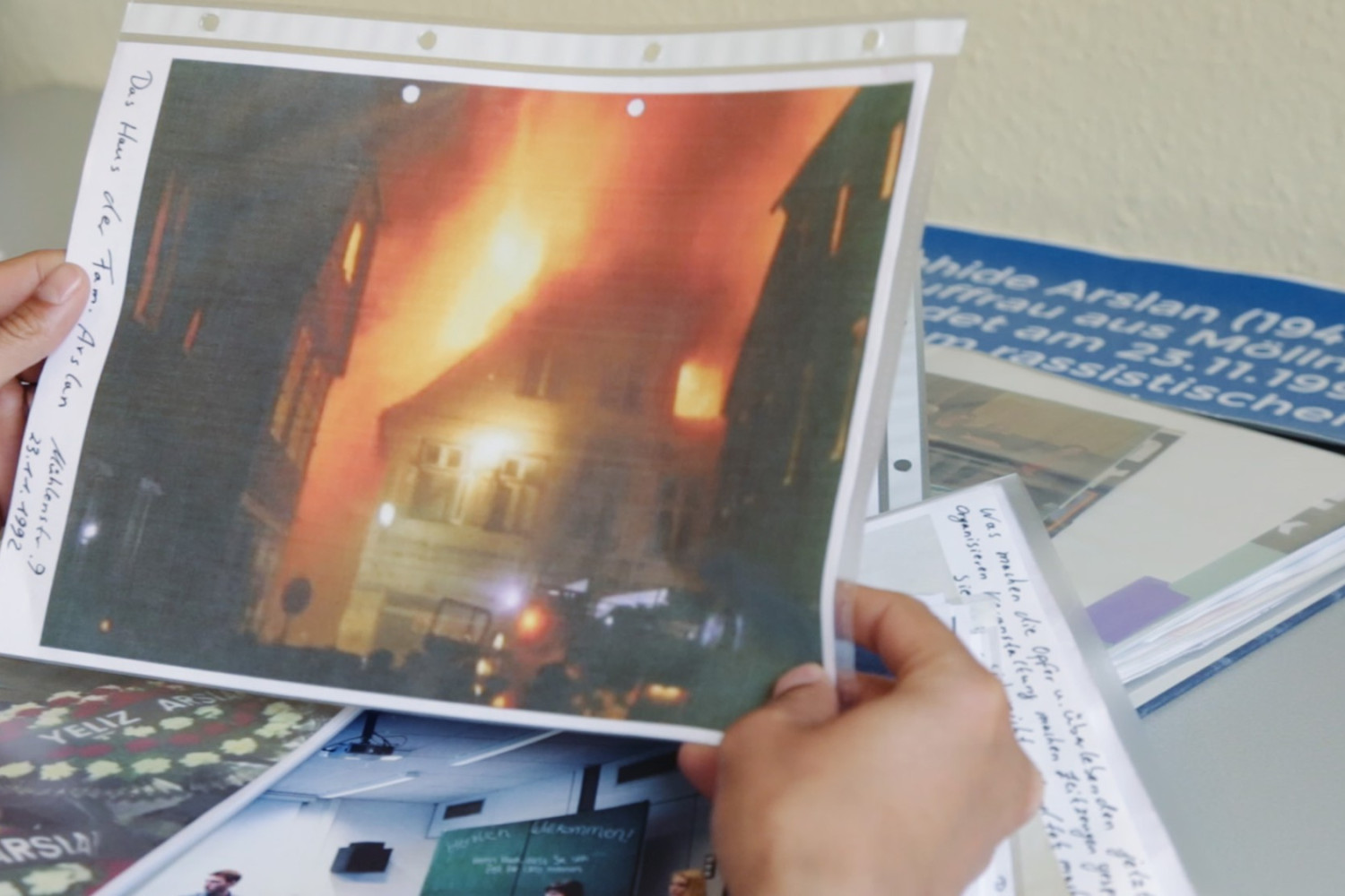 Szene aus dem Film "Der zweite Anschlag". Eine Person h&auml;lt ein Foto, auf dem man ein brennendes Haus sieht.