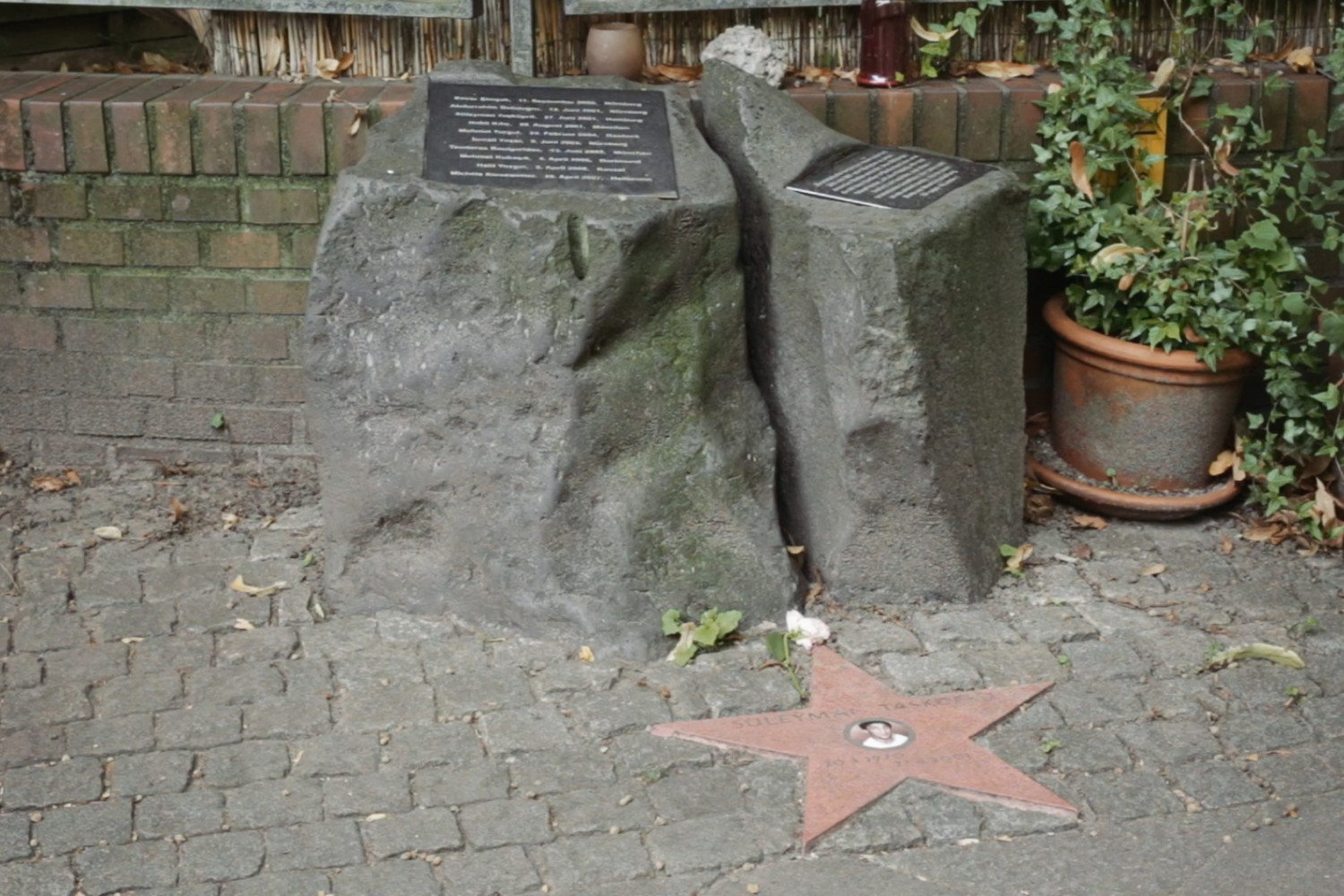 Szene aus dem Film "Der zweite Anschlag", in der man ein Denkmal f&uuml;r eine ermordete Person sieht.
