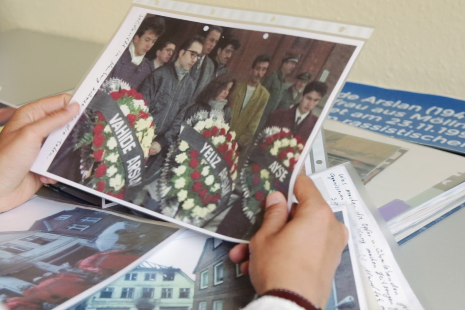 Szene aus dem Film "Der zweite Anschlag". Eine Person h&auml;lt ein Foto, auf dem Menschen mit Trauerkr&auml;nzen zu sehen sind.