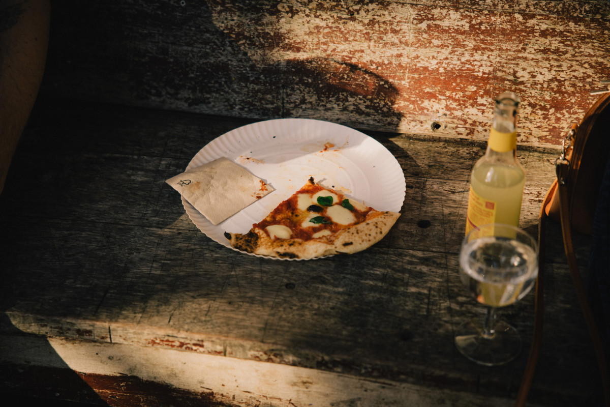 Ein St&uuml;ck Pizza und eine Limo auf einer sonnigen Bank