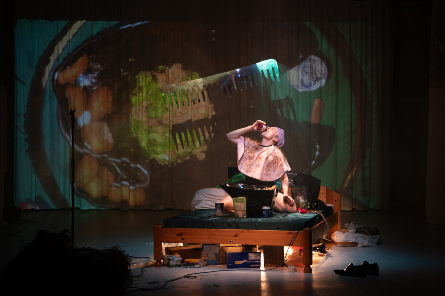 Hendrik Quast im OP-Nachthemd auf der B&uuml;hne, er trinkt einen Schnaps