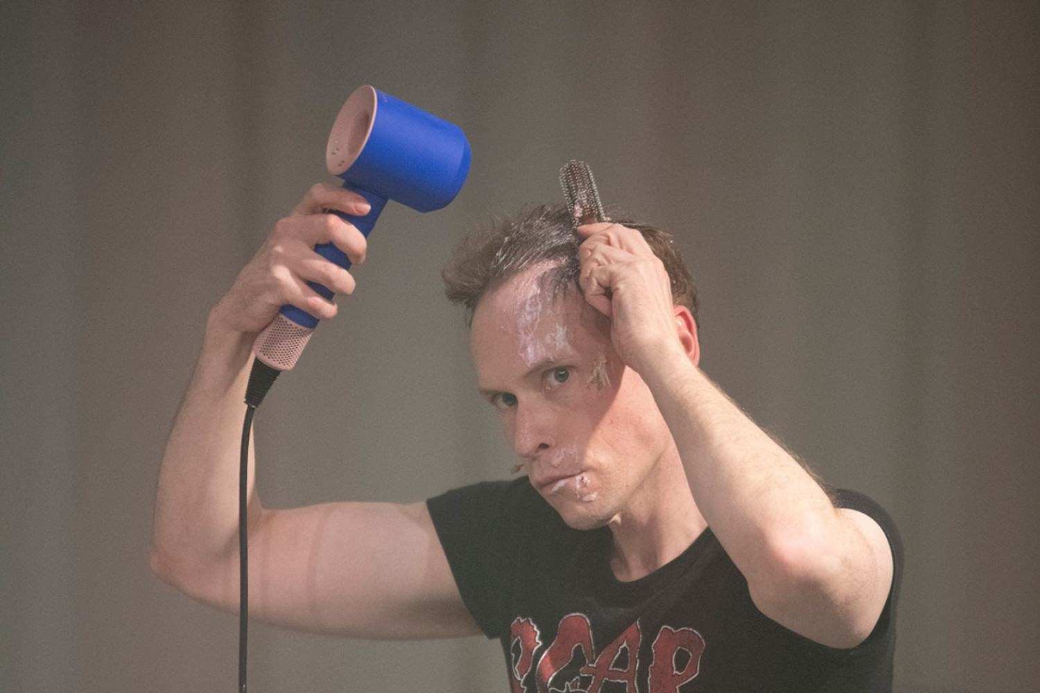 Hendrik Quast sitzt im Jogginganzug auf einem Bett und f&ouml;hnt sein Haar