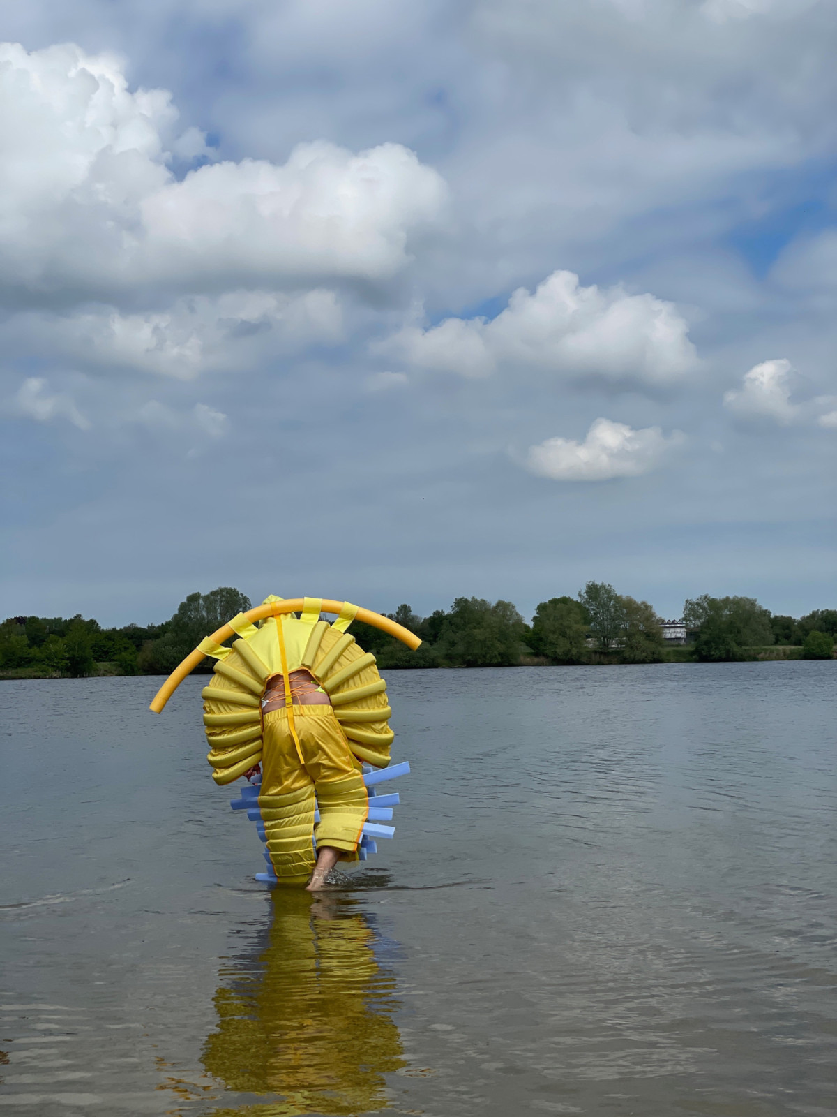 Eine Person im gelben Floating Anzug watet durch flaches Wasser