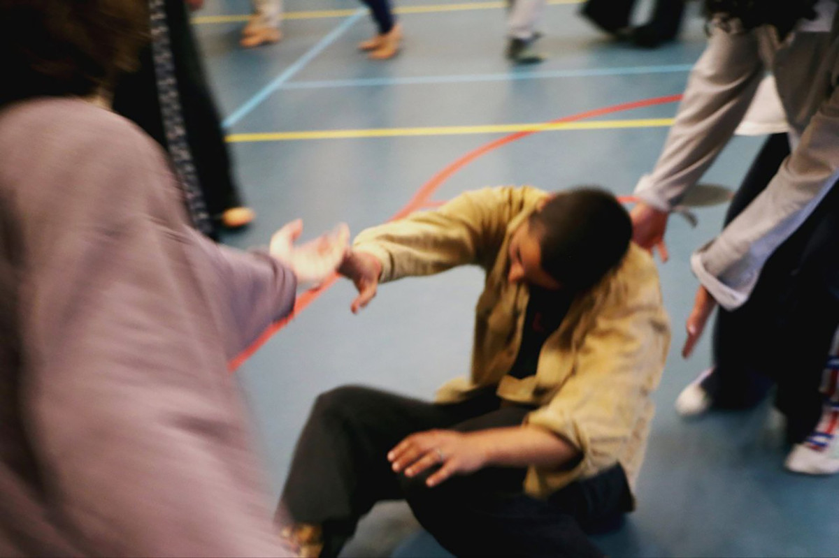 A slightly blurred photo of people doing contact improvisation in a gym.