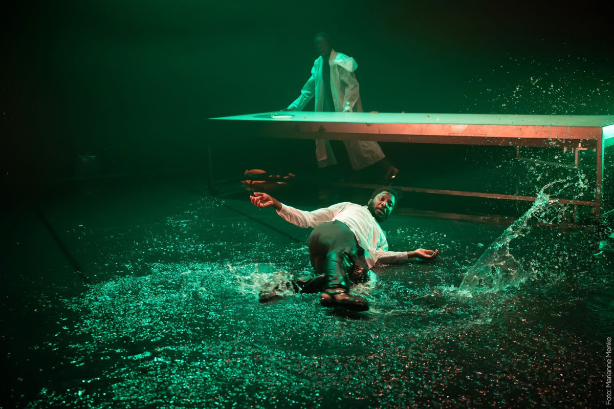 Performer liegt im Wasser auf der Bühne