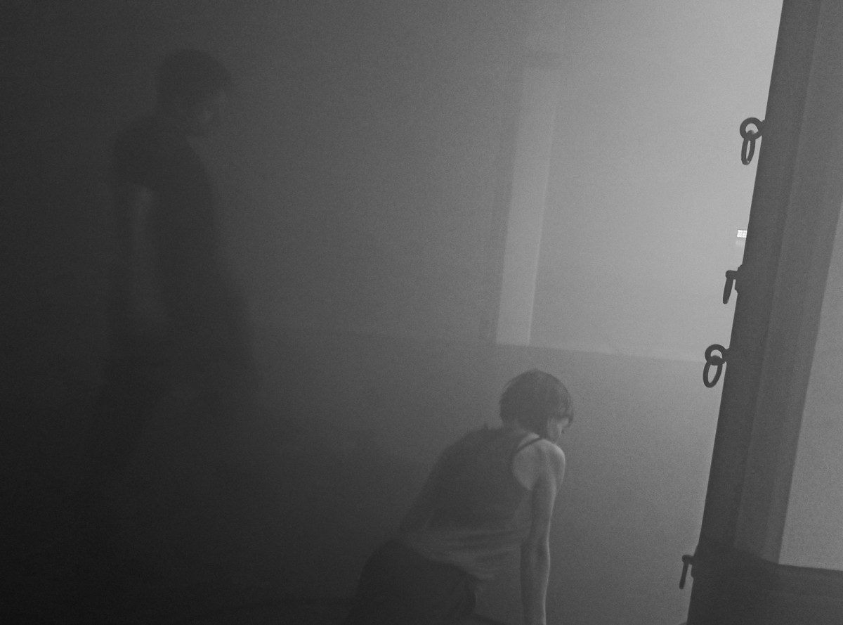 Zwei Performer*innen in einem dunklen, nebligen Raum