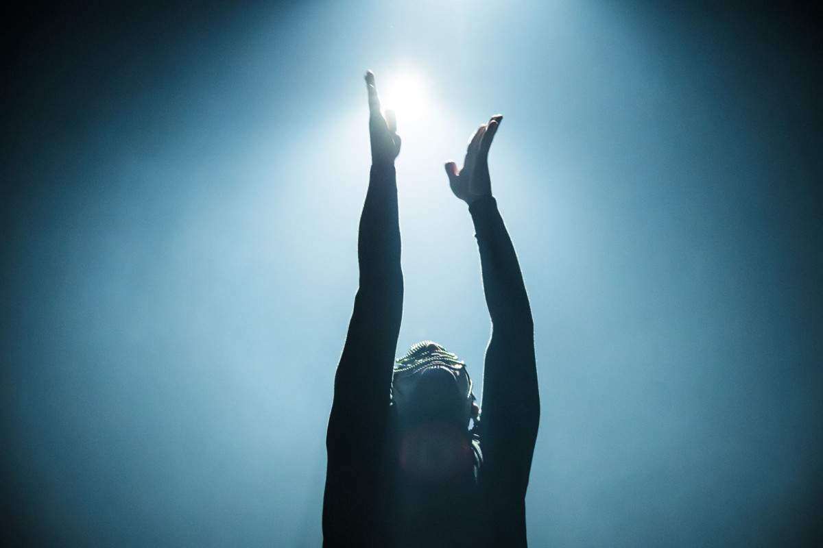 Ein Performer streckt die Arme nach oben zum Licht