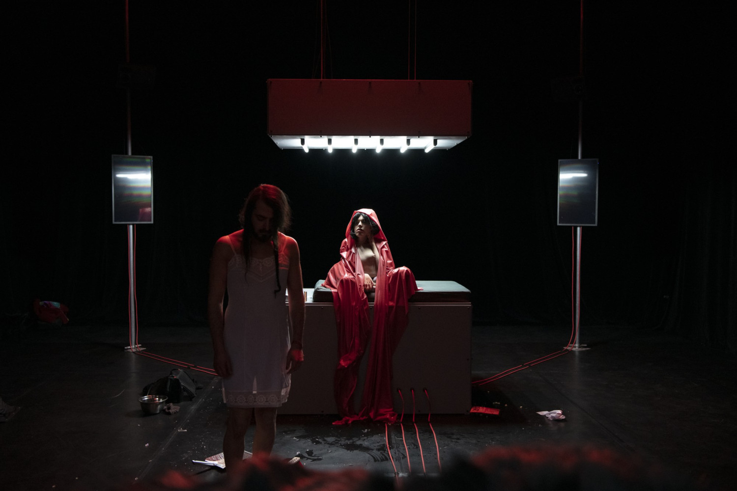 Zwei Performer*innen, eine Person im wei&szlig;en Nachtkleid und die andere mit einem roten Kaputzen-Umhang
