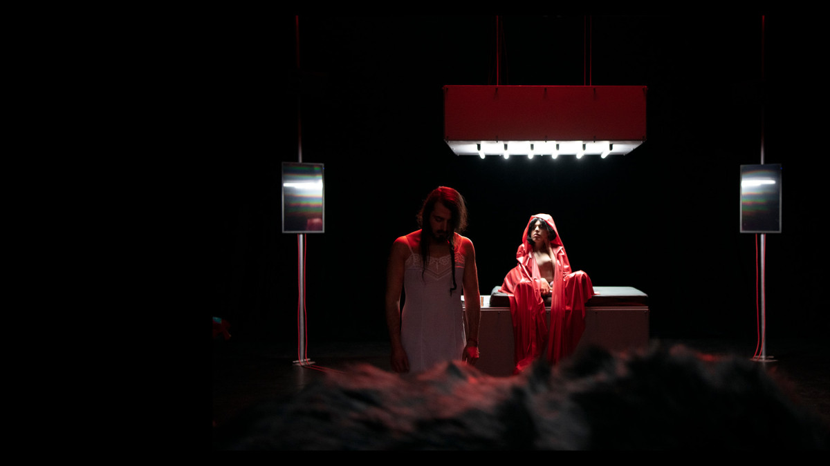 Zwei Performer*innen, eine Person im wei&szlig;en Nachtkleid und die andere auf mit einem roten Kaputzenumhang